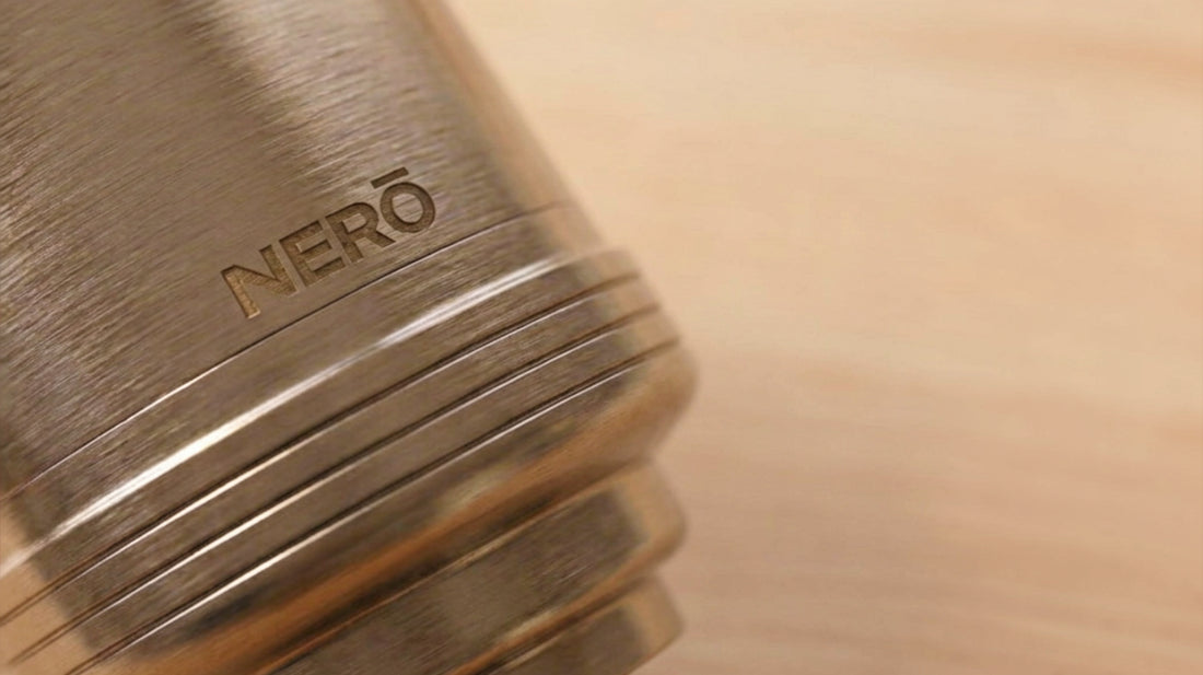 Macro of the brushed stainless steel NERŌ filter body, engraved with the NERŌ name, on a warm timber benchtop